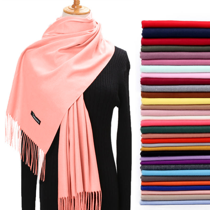 Pink scarf on a mannequin with a stack of folded scarves in various colors.