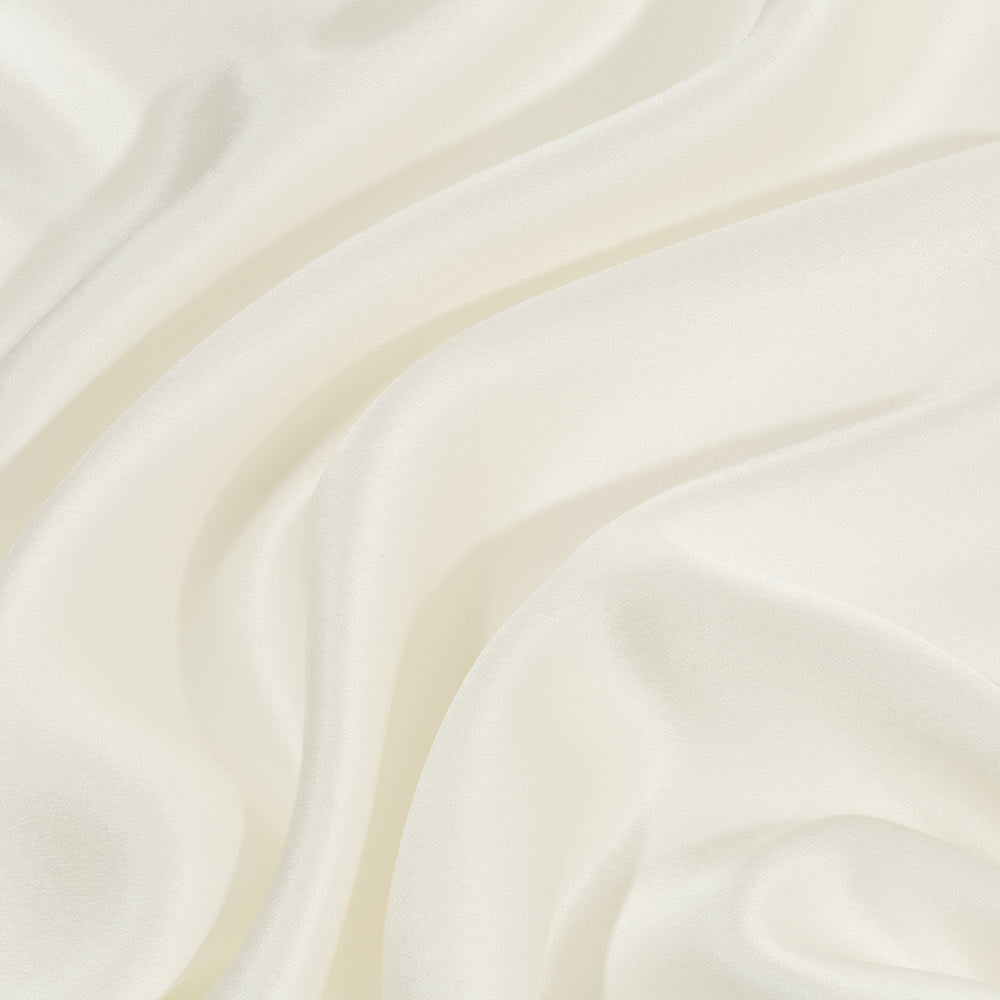Close-up of smooth, ivory silk pillowcase with soft folds