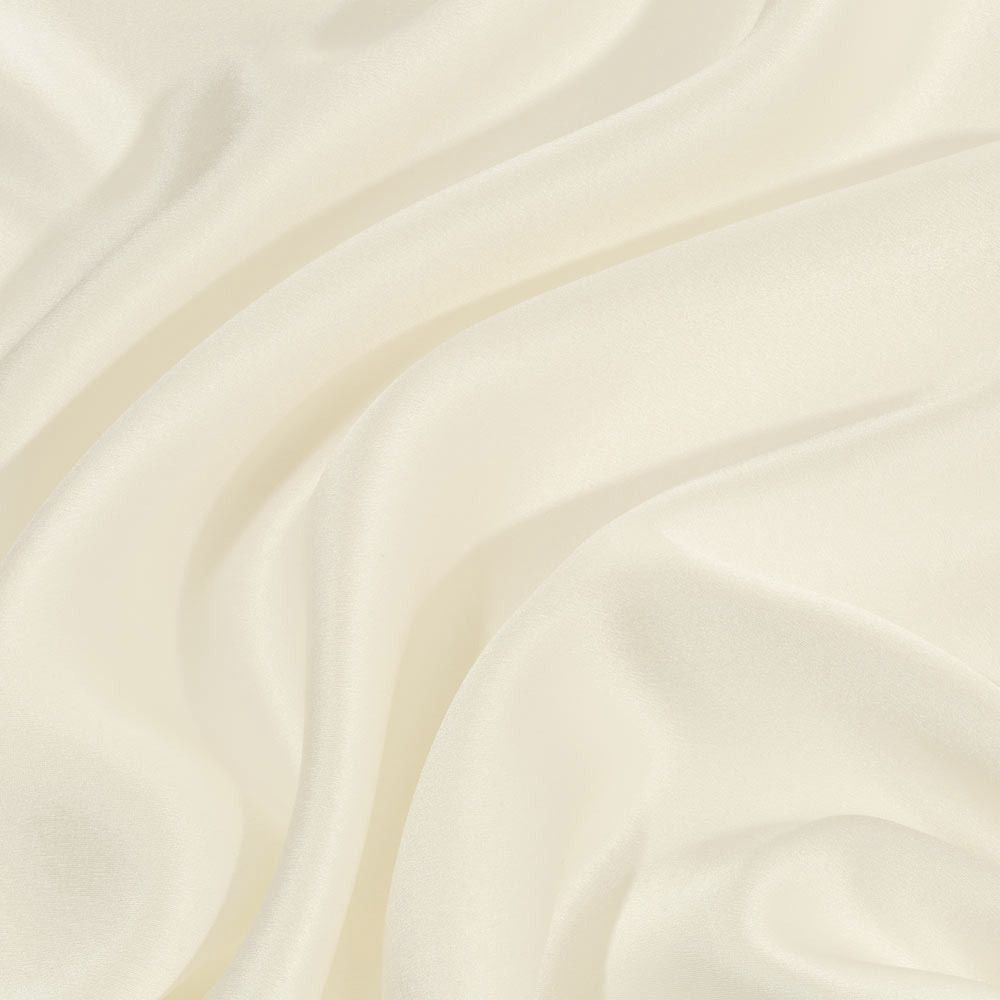 Close-up of smooth, ivory silk pillowcase with soft folds